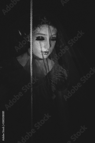 Spooky black and white photo of a halloween doll weraing veil