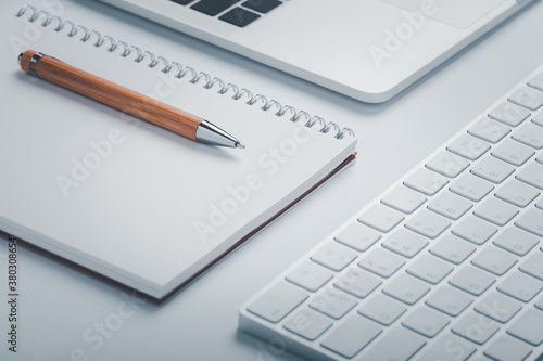 Closeup shot of brown pen with notebook and keyboard on workspace.