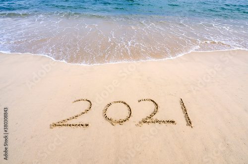 2021 year message handwritten in sand on beautiful beach background. New Years concept.