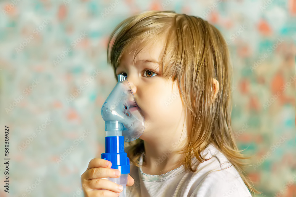 A cute little girl is undergoing medical treatment with inhalations and a nebulizer at home.A little girl is sitting and doing steam inhalation for coughing.The concept of respiratory tract treatment A cute little girl is undergoing medical treatment with inhalations and a nebulizer at home.A little girl is sitting and doing steam inhalation for coughing.The concept of respiratory tract treatment