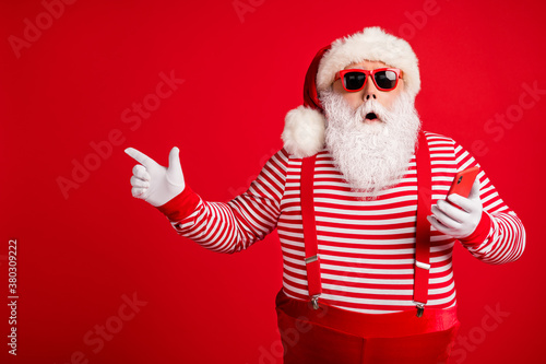 Portrait of his he nice handsome amazed bearded fat overweight Santa using gadget demonstrating copy space bargain December novelty isolated bright vivid shine vibrant red color background © deagreez