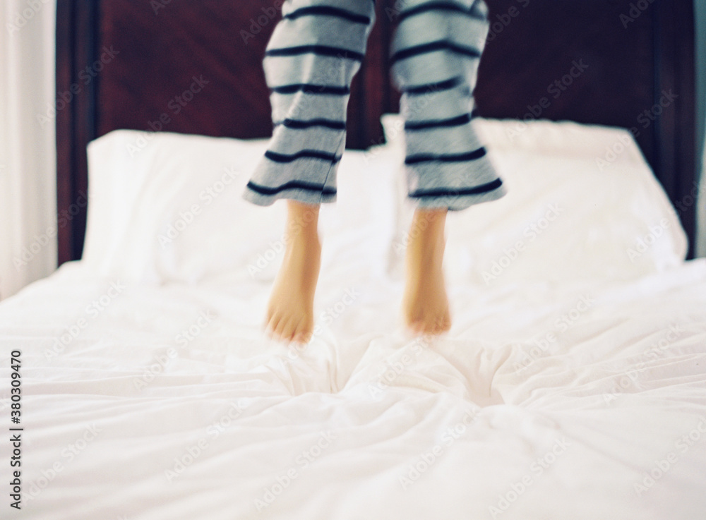 Boy jumping on bed in striped pants Boy jumping on bed in striped pants