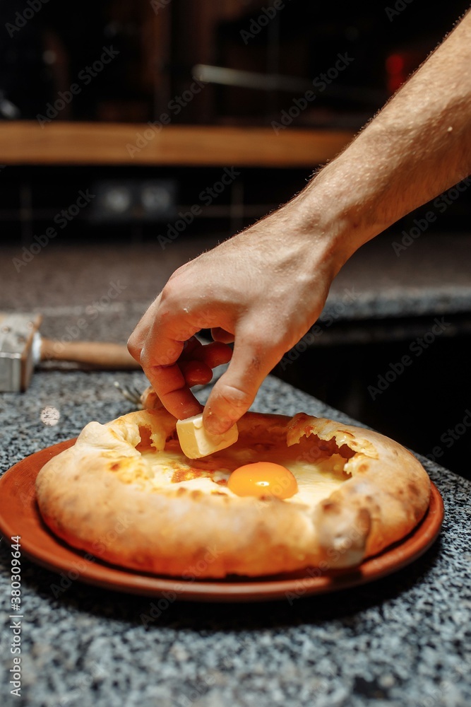 Baker hands preparing khachapuri on kitchen table. cook making traditional georgian treat with raw dough and egg. recipe concept