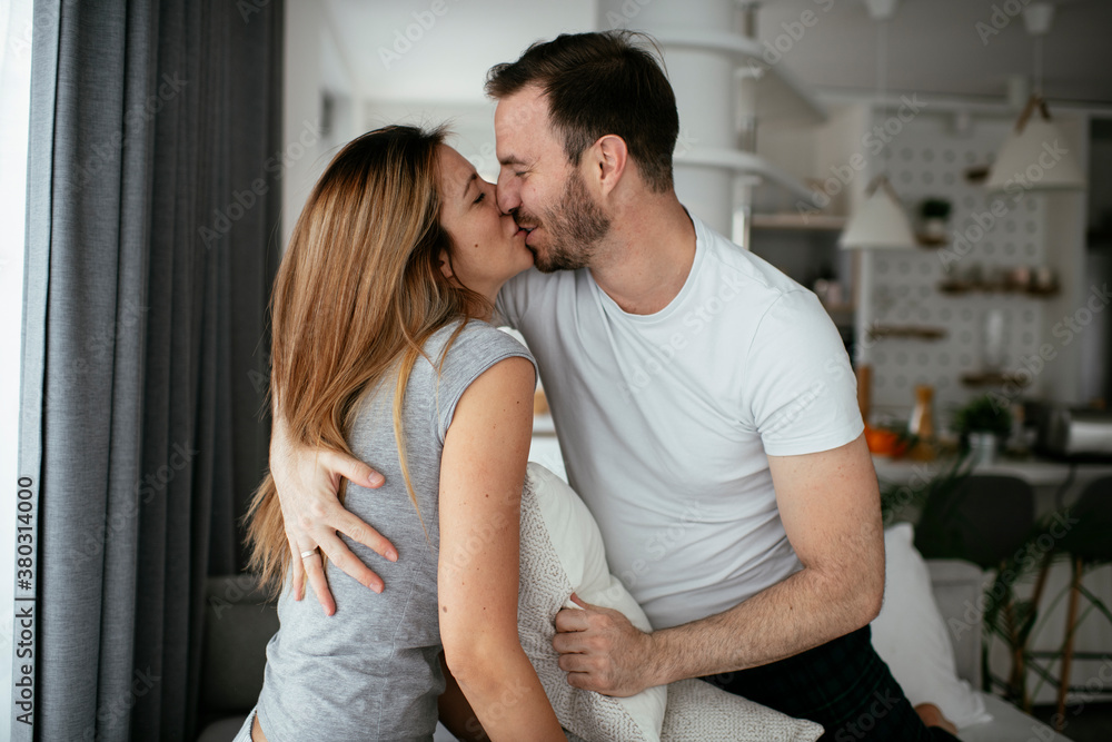 Young couple fighting pillows on the bed. Happy couple having fun at home. Young couple fighting pillows on the bed. Happy couple having fun at home.
