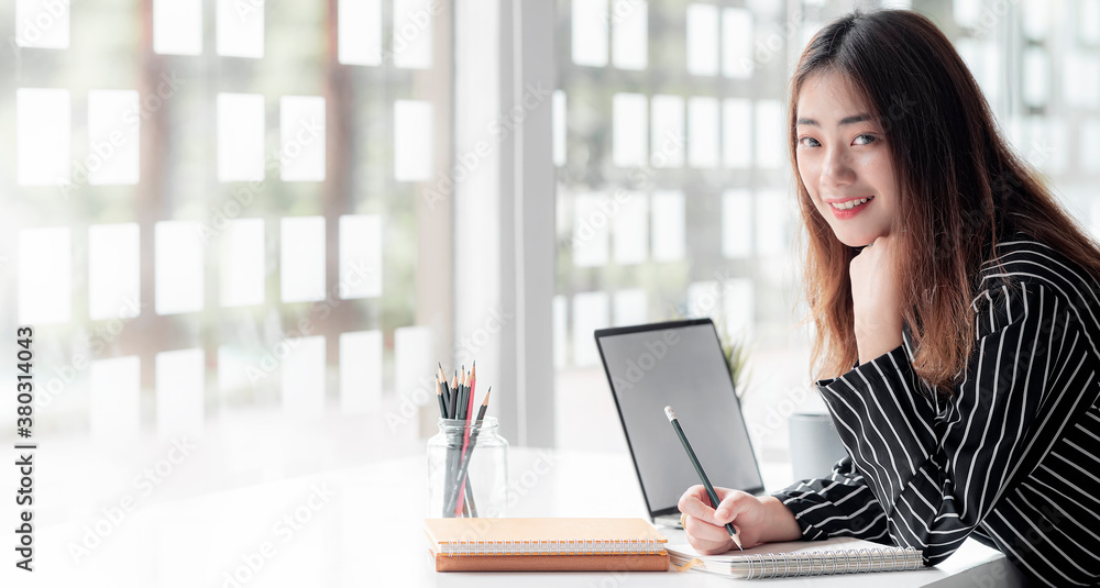 Young female designer working on her project while smiling to the camera in office room. Young female designer working on her project while smiling to the camera in office room.