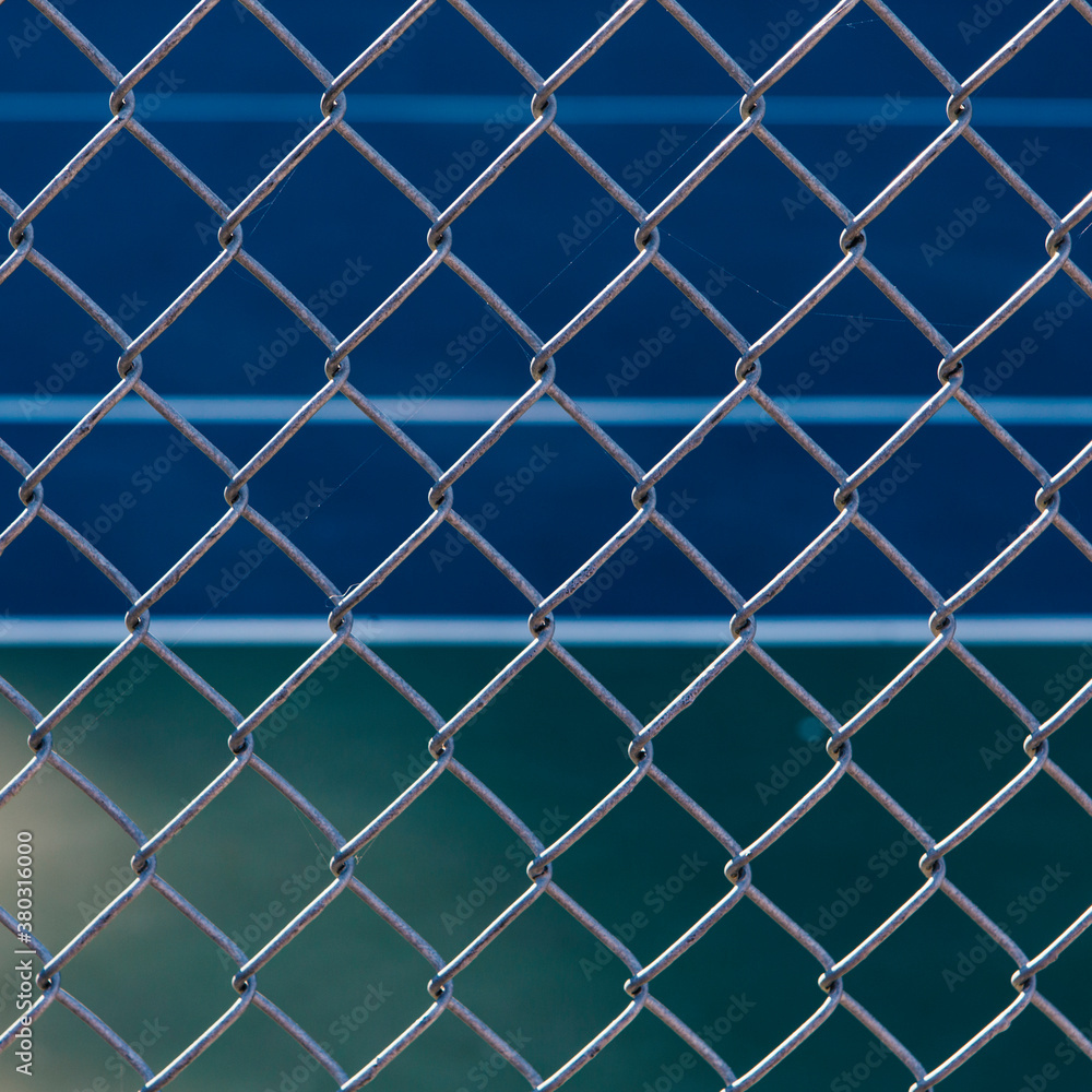 Close of up chain link fence, basketball court in background Close of up chain link fence, basketball court in background