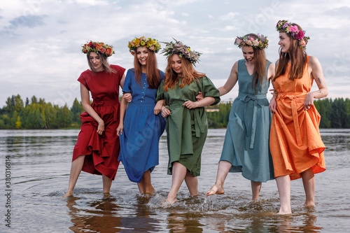 Lovely girls in flower wreaths in nature. Ancient pagan origin celebration concept. Summer solstice day. Mid summer. Ancient rituals.