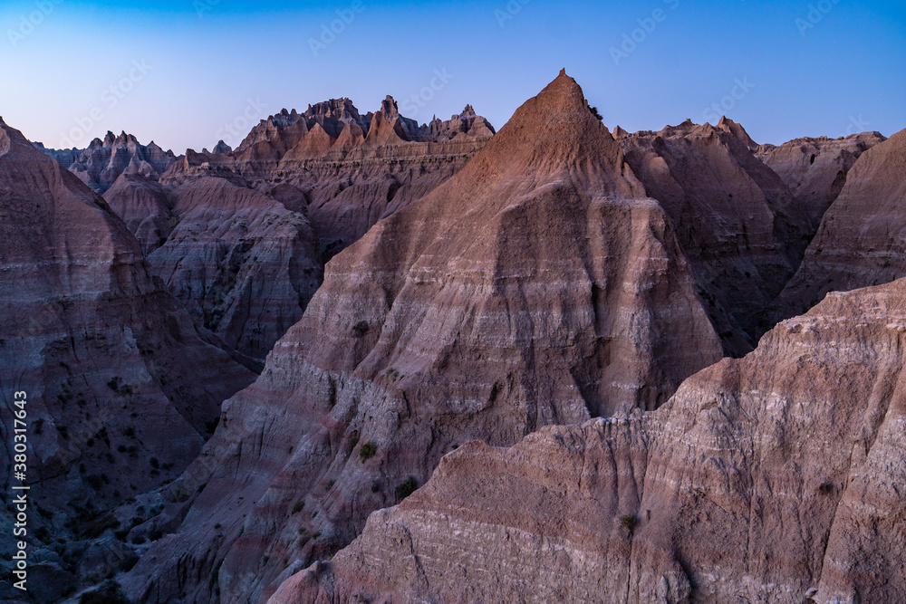 Mounds and canyons of layered sedimentary rock with summits and ridges soaring towards the blue sky, Badlands National Park, South Dakota