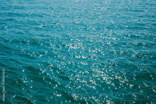 Background ocean wave with bokeh from sunlight reflected on water surface.