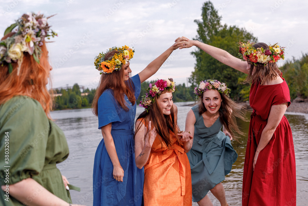 Lovely girls in flower wreaths in nature. Ancient pagan origin celebration concept. Summer solstice day. Mid summer. Ancient rituals.