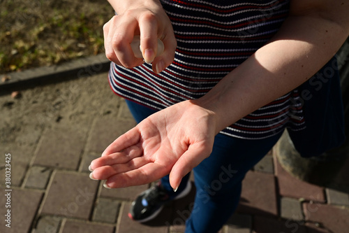 A young woman standing outdoor disinfects her hands according to the rules of hygiene during an epidemic period. Banner with quarantine, anti coronavirus and handwashing concept