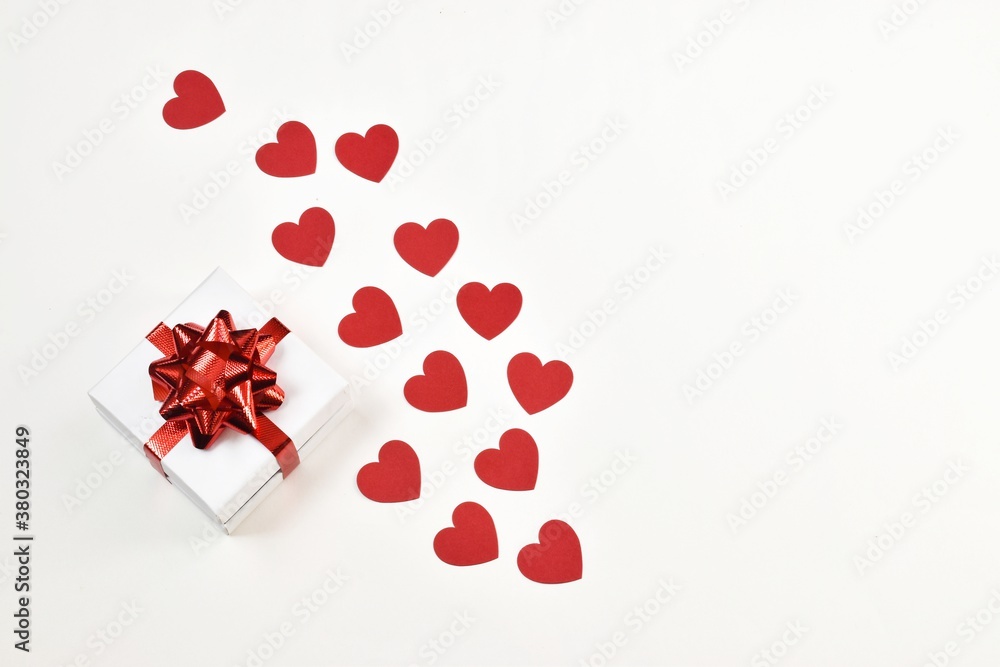 White gift box with a red ribbon with hearts on a white background. Postcard for Valentine's Day or Mother's Day, Christmas and New year. copy space, flat lay. Holiday concept.