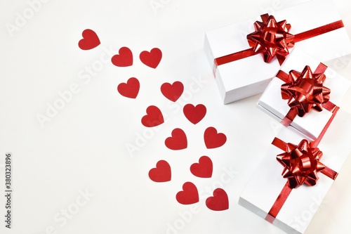 White gift boxes with a red ribbon with hearts on a white background. Postcard for Valentine's Day or Mother's Day, Christmas and New year. copy space, flat lay. Holiday concept.