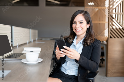 Smiling businesswoman using mobile phone at desk