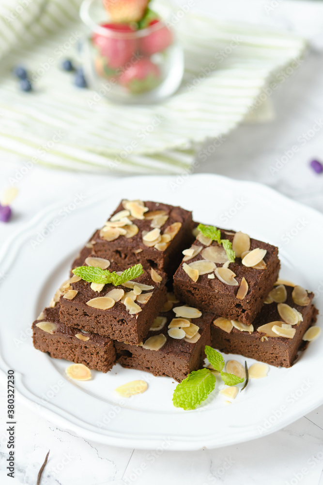 Squares Chocolate brownie with almond sliced set on white cafe table. Squares Chocolate brownie with almond sliced set on white cafe table.