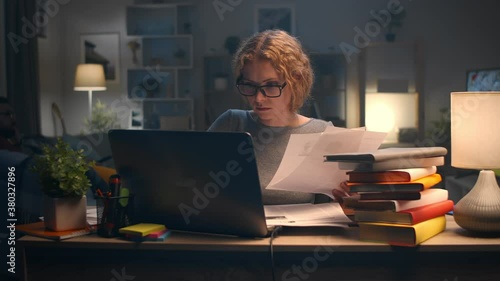 Young beautiful woman working on laptop late at night in her apartment