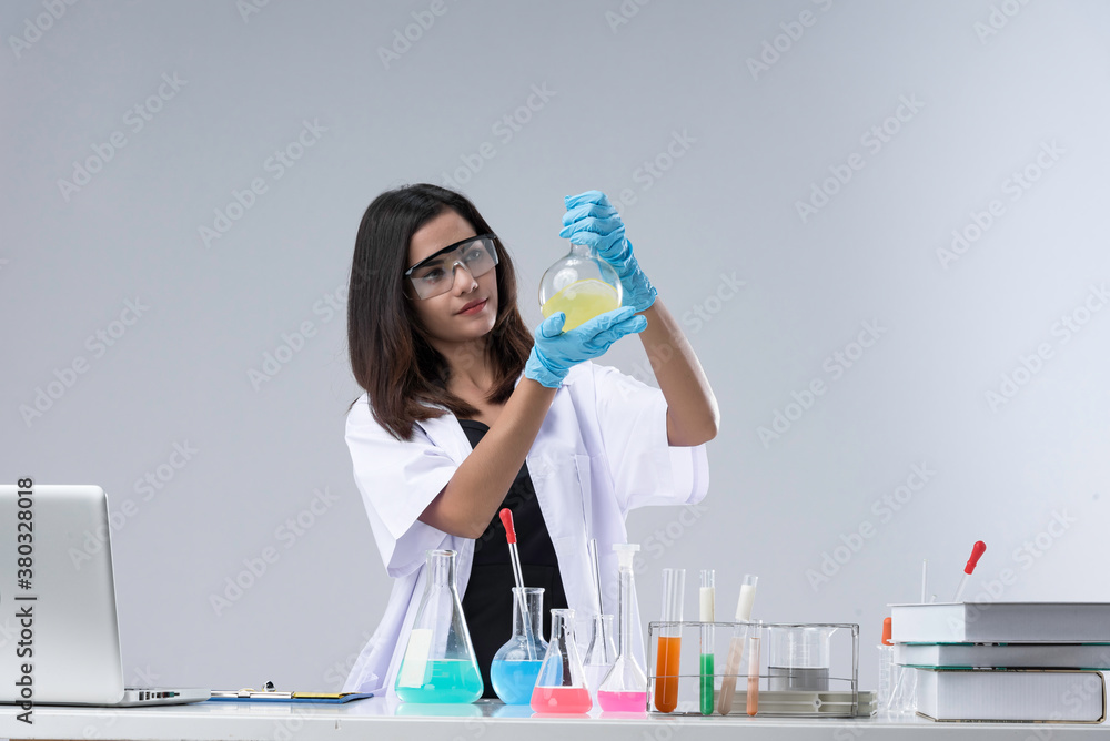 Cheerful chemist woman in lap, or graduate student in lab coat ane protetive wear work,check and test chemistry.