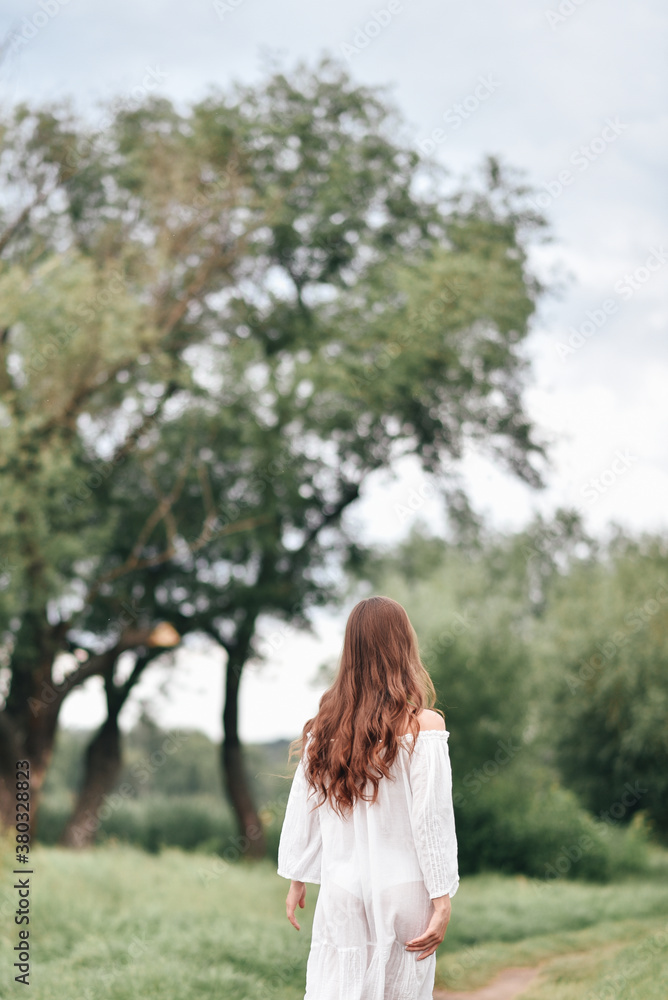 Young beautiful girl in white dress runs around in nature scattering hair in the wind Young beautiful girl in white dress runs around in nature scattering hair in the wind
