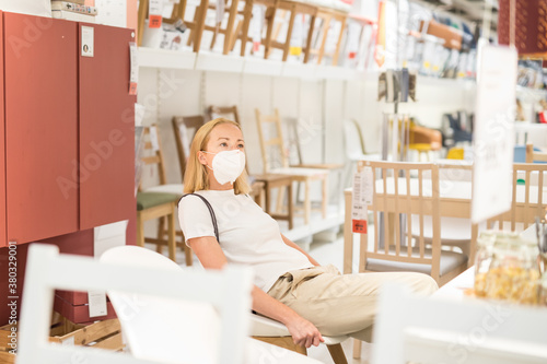 New normal during covid epidemic. Caucasian woman shopping at retail furniture and home accessories store wearing protective medical face mask to prevent spreading of corona virus.