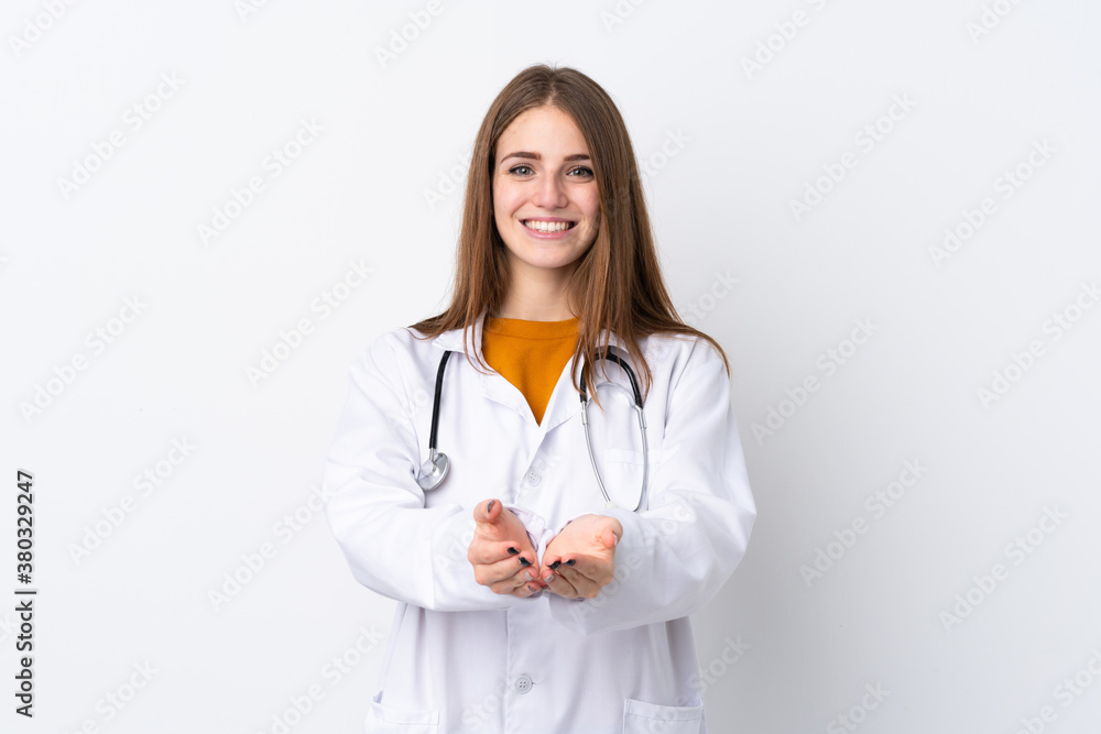 Young woman over isolated background wearing a doctor gown and holding something Young woman over isolated background wearing a doctor gown and holding something