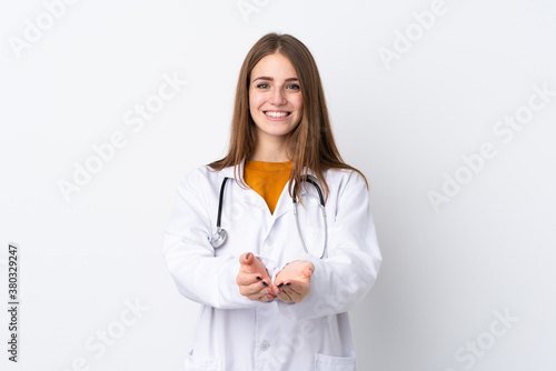 Young woman over isolated background wearing a doctor gown and holding something