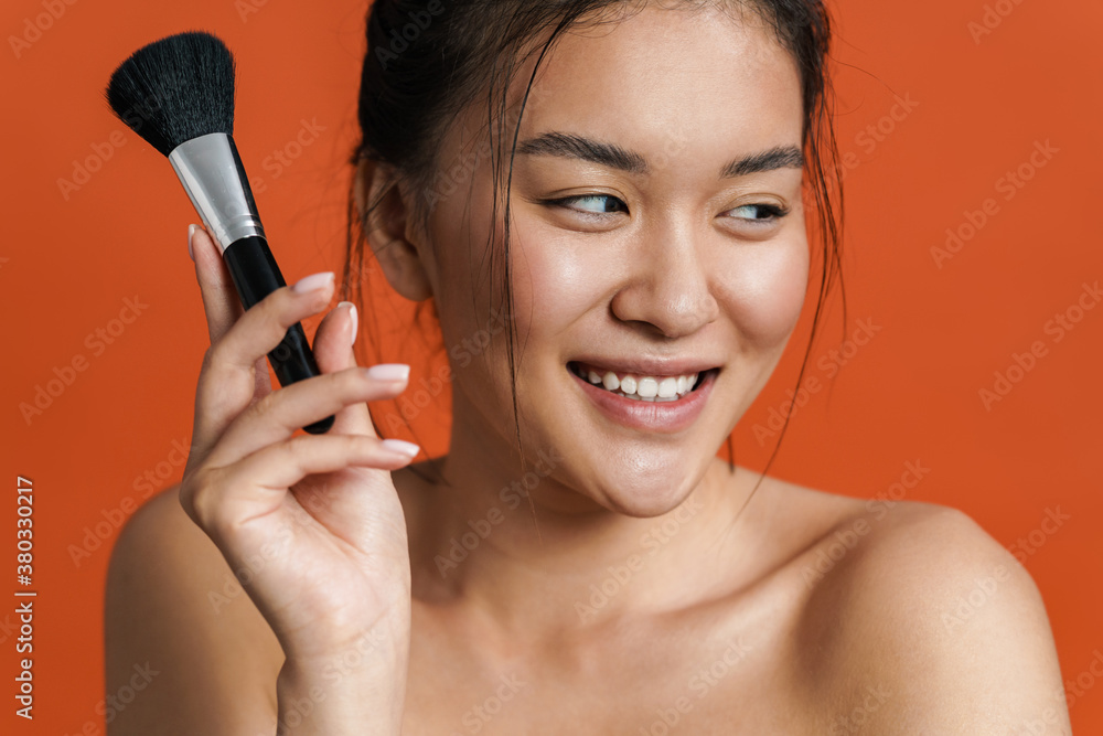 Image of cheerful shirtless asian girl posing with powder brush Image of cheerful shirtless asian girl posing with powder brush