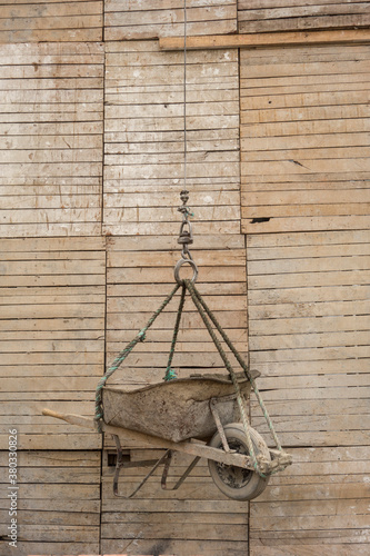 Old fashioned wheelbarrow being hauled up a wire at construction site photo