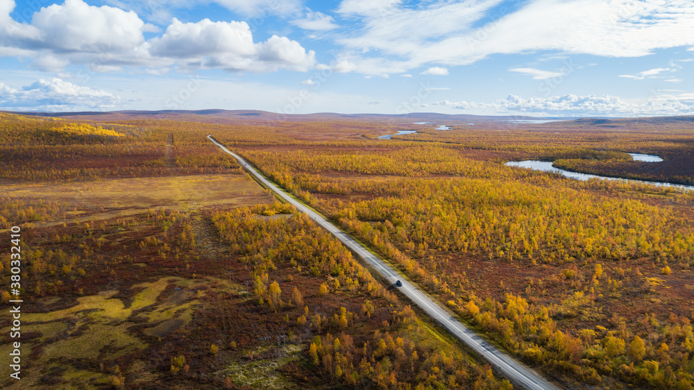 Aerial sunny fall autumn view of country road, Lapland, Kilpisjarvi, Finland. Blue sky and clouds. Shot from drone.