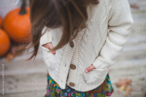 Close up of girl wearing cozy white cable knit sweater with pumpkins