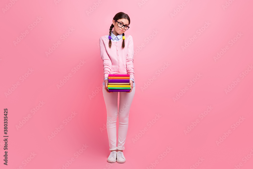 Full body photo of funny student lady two braids hold many books diligent pupil addicted reader shy librarian wear shirt pullover pants sneakers specs isolated pastel pink color background Full body photo of funny student lady two braids hold many books diligent pupil addicted reader shy librarian wear shirt pullover pants sneakers specs isolated pastel pink color background