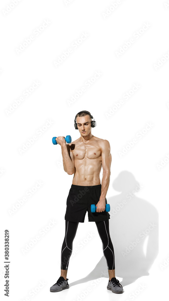 Weights. Stylish young male athlete practicing on white studio background, portrait with shadows. Sportive fit model in works out in motion and action. Body building, healthy lifestyle, style concept. Weights. Stylish young male athlete practicing on white studio background, portrait with shadows. Sportive fit model in works out in motion and action. Body building, healthy lifestyle, style concept.