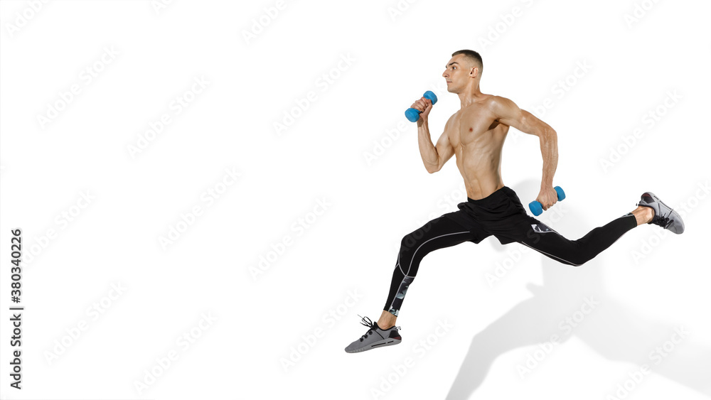 Running, jumping. Stylish young male athlete on white studio background, portrait with shadows. Sportive fit model in motion and action. Body building, healthy lifestyle, style concept. Flyer