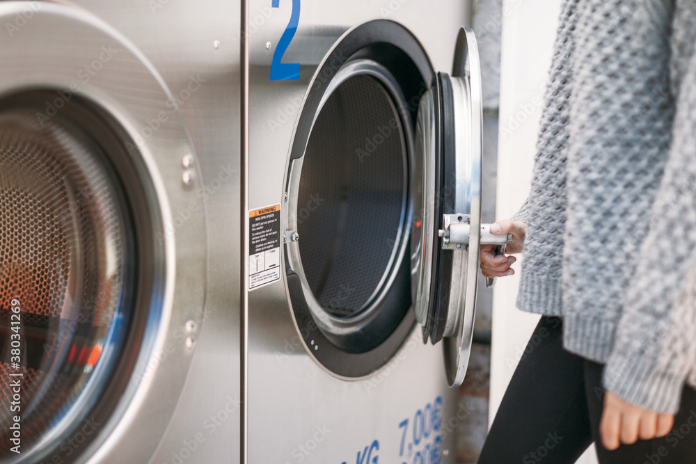 Closeup of woman open a washing machine on a launderette. Closeup of woman open a washing machine on a launderette.