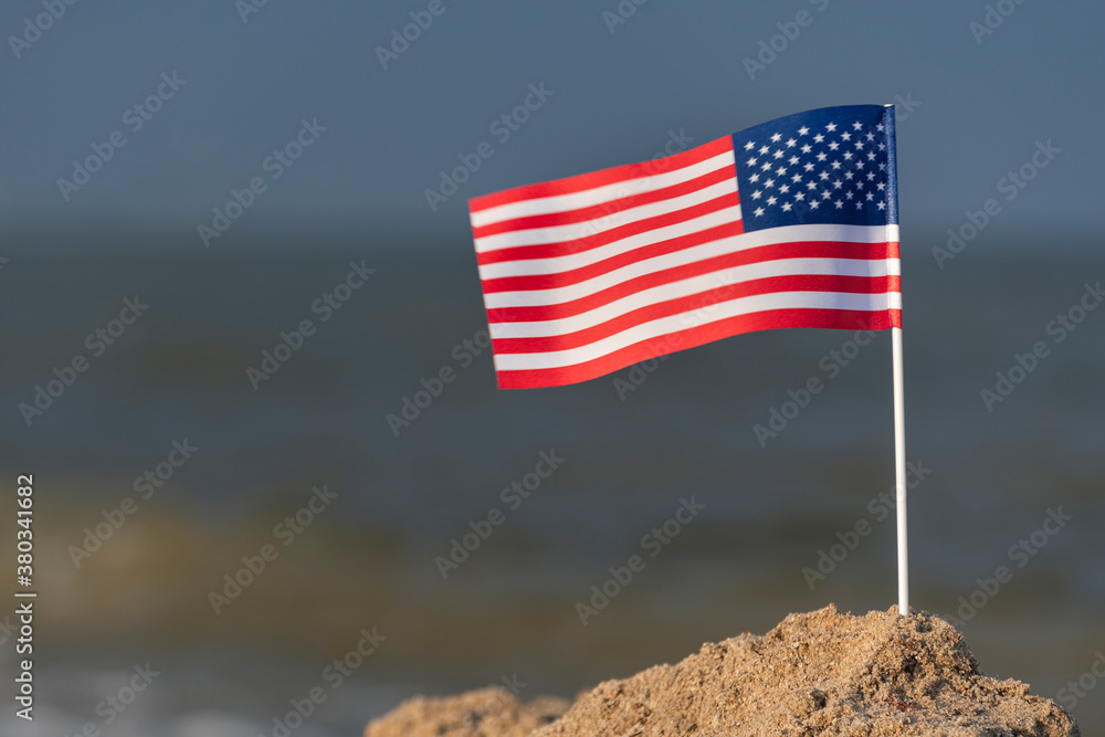 Naklejka premium Flag of USA on the beach. National flag of America, sea background.