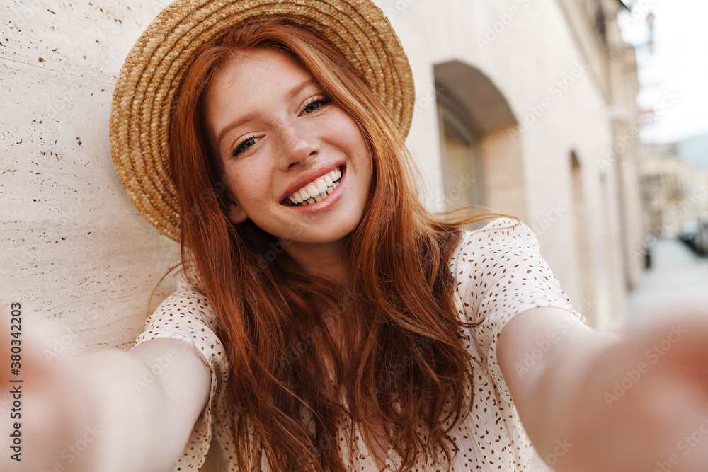 Image of joyful ginger girl smiling while taking selfie photo