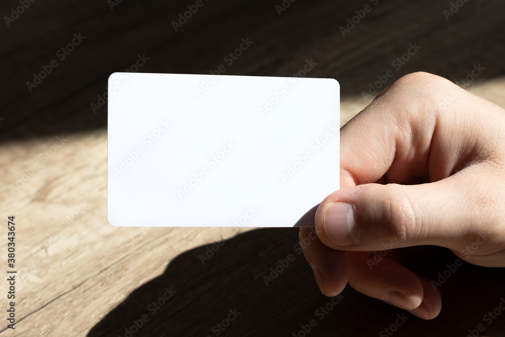 Obraz premium Mockup business cards on man's hands on a wooden background.