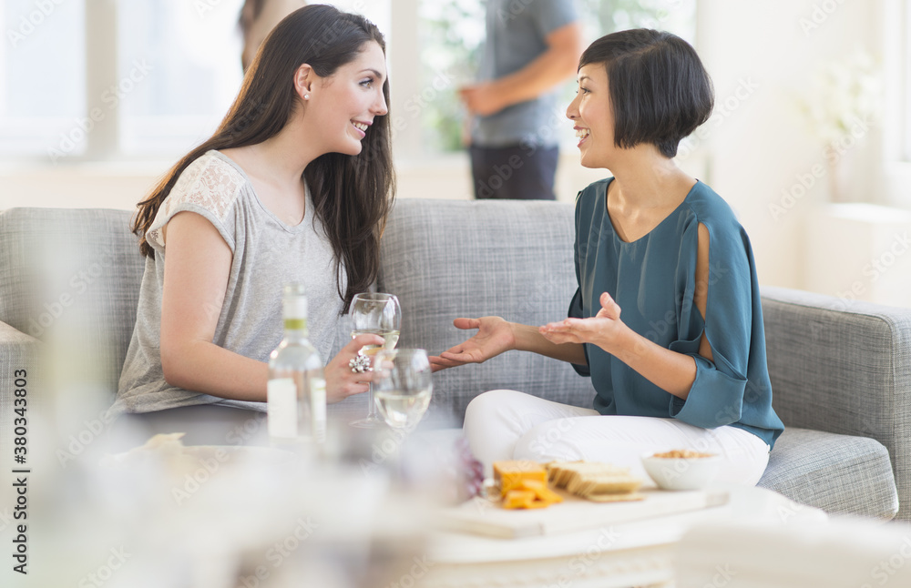 Two friends sitting on sofa and talking Two friends sitting on sofa and talking