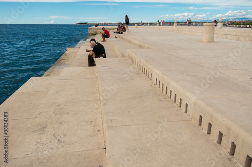 Zadar / Croatia - September 2 2020: People sitting by Sea Organ, an architectural sound art located in Zadar, Croatia. © eyecon