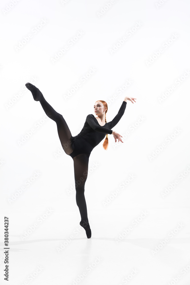 Weightless. Young and graceful ballet dancer in minimal black style isolated on white studio background. Art, motion, action, flexibility, inspiration concept. Flexible caucasian ballet dancer.