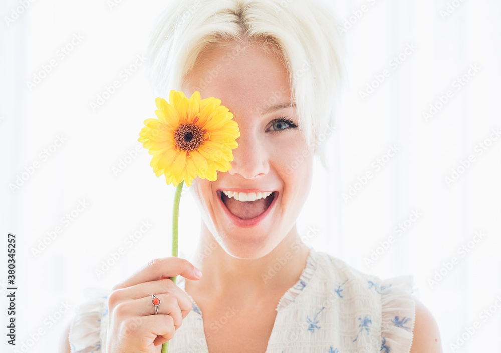 Portrait of blonde woman holding yellow flower Portrait of blonde woman holding yellow flower