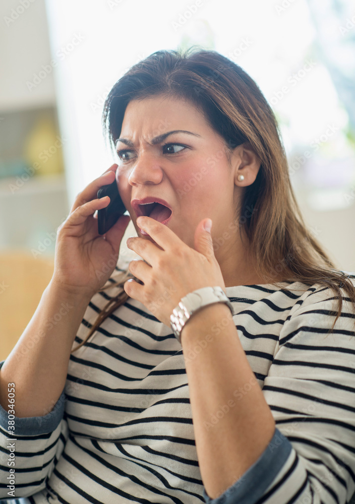 Surprised woman sitting on sofa with mobile phone Surprised woman sitting on sofa with mobile phone