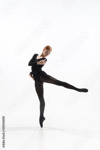 Light. Young and graceful ballet dancer in minimal black style isolated on white studio background. Art, motion, action, flexibility, inspiration concept. Flexible caucasian ballet dancer.