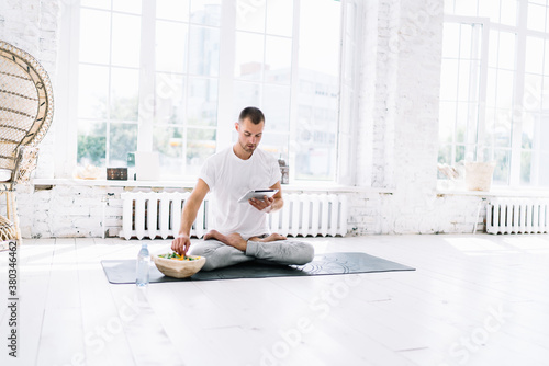 Confident man with tablet in lotus pose