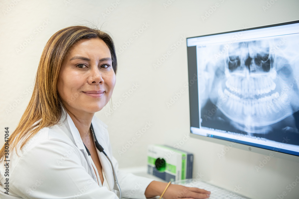 A dentist looking at x-rays in a computer