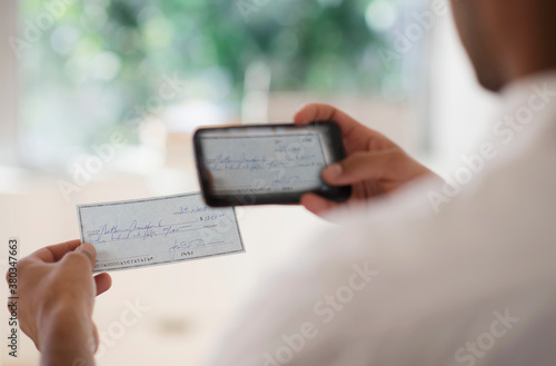 Man taking photo of banking check with cell phone