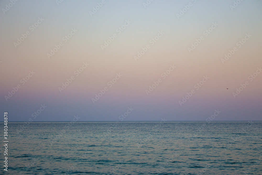 Seascape with seagull over water. Sunset over the sea. Calm evening on island beach. Tranquility concept. Dramatic evening sky in dusk. Horizon over water. Bay landscape.