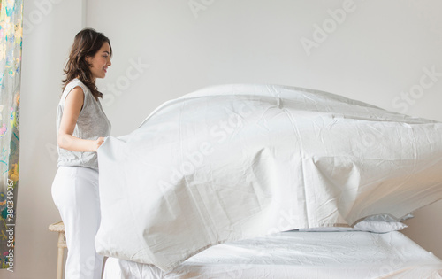 Young woman making bed photo