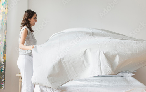 Young woman making bed