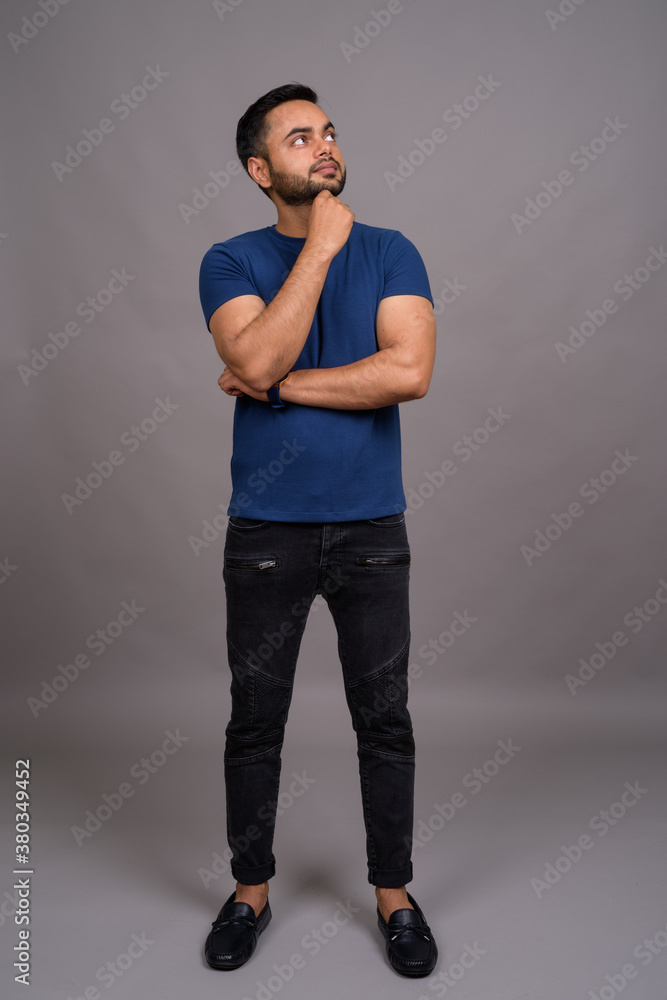 Young bearded Indian man against gray background Young bearded Indian man against gray background