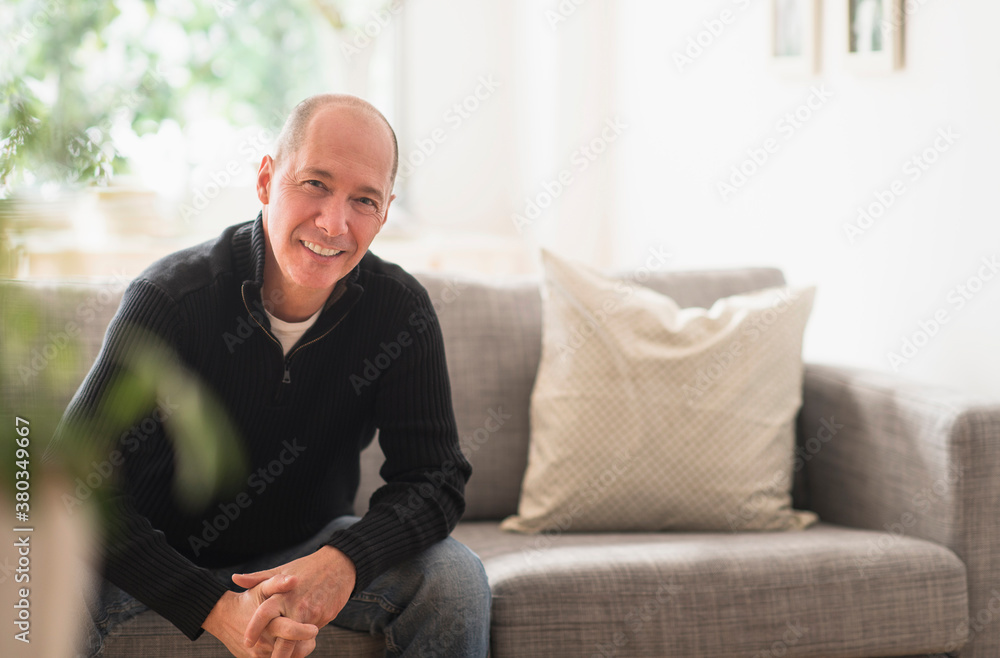 Portrait of smiling mature man relaxing on sofa in living room Portrait of smiling mature man relaxing on sofa in living room